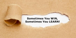 The text Sometimes You WIN Sometimes You LEARN, appearing behind torn brown paper. Motivational quote.
